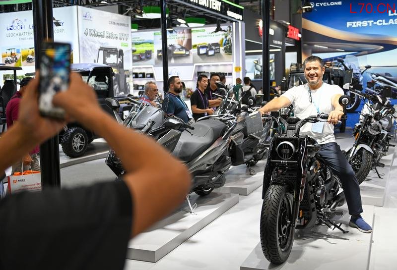 去年10月,客商在138届广交会展馆摩托车展区与摩托车产品合影留念。新华社
